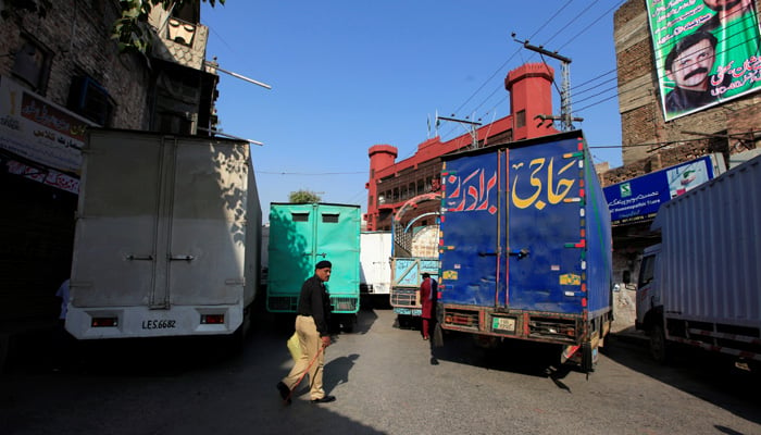 A policeman walks next to trucks, which used to block a venue of a planned protest gathering organised by Awami Muslim League