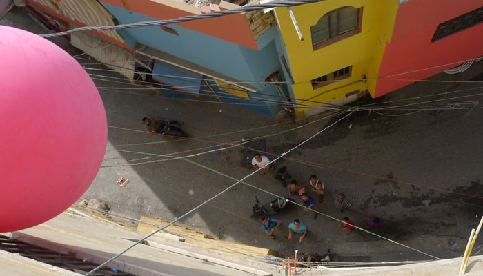 Participants watch from below as the red balloon sails above a spot in the camp [Courtesy of Greening Bourj al-Shamali] 