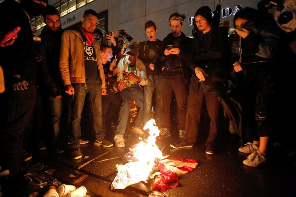 Demonstrators burn the U.S. flag outside Trump Tower during a march against President-elect Donald Trump in Manhattan, New York