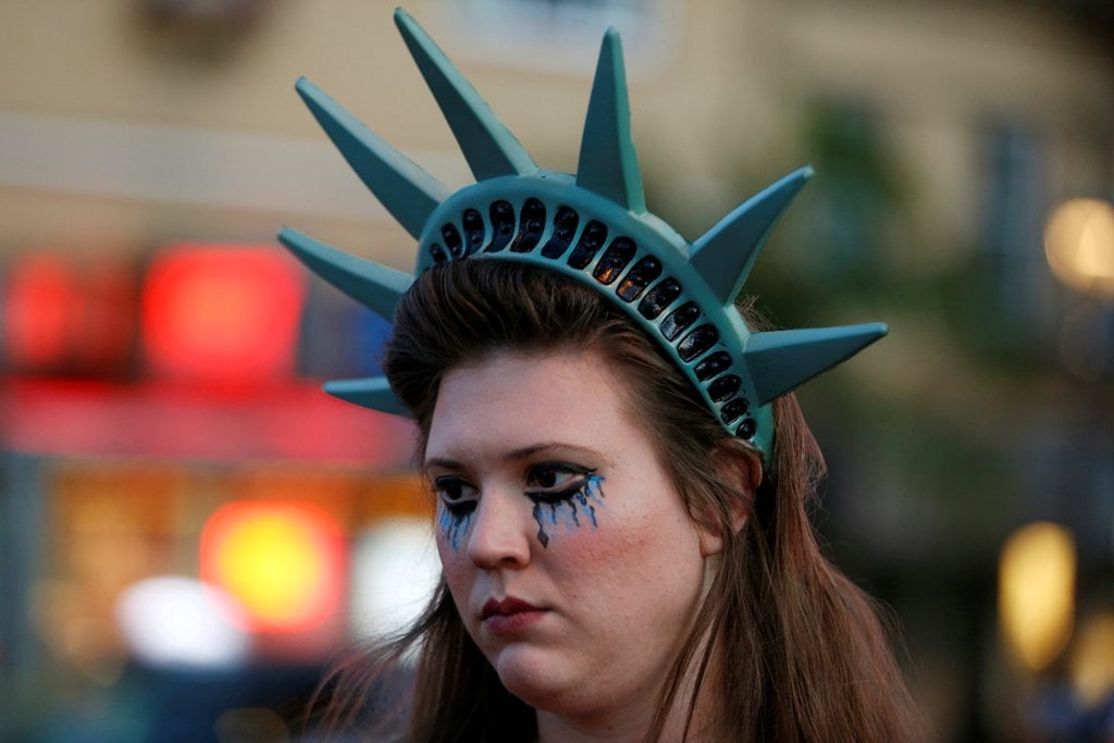 A demonstrator wears a headpiece depicting the crown of the Statue of Liberty during a protest in San Francisco, California