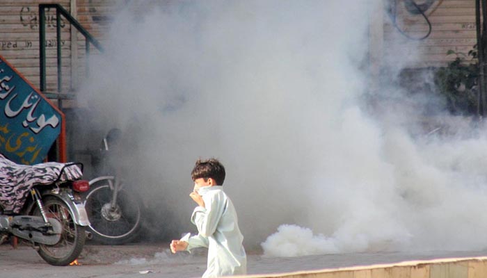  A boy seen passing by a tear gas shell fired by police to disperse the supporters of Awami Muslim League near Committee Chowk.