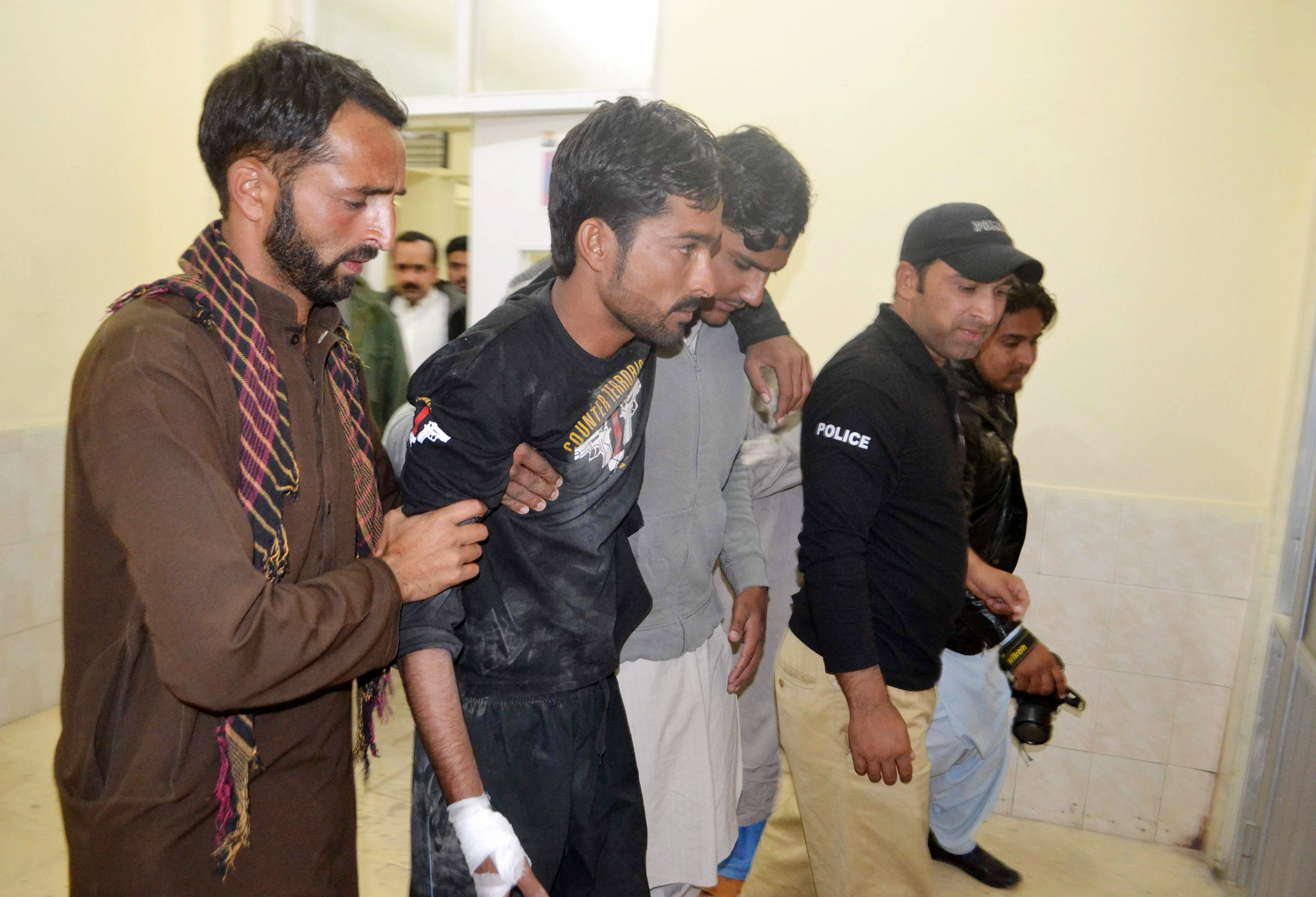 Police help an injured colleague into the hospital after militants attacked the Balochistan Police College in Quetta.