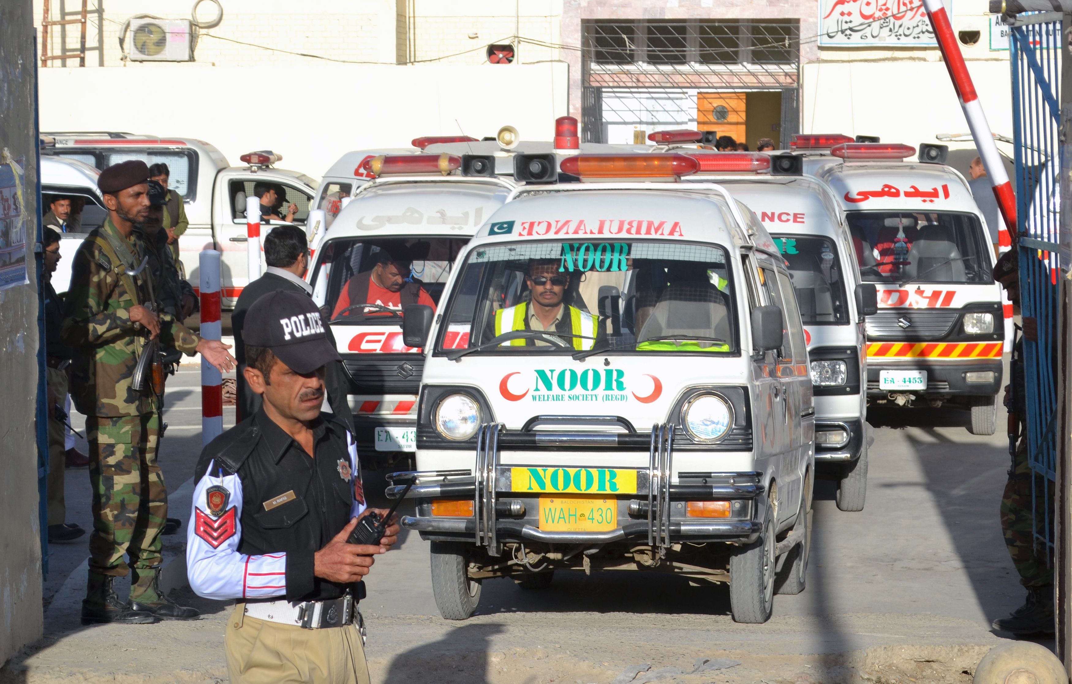 Security personnel stand guard as an ambulance carrying the coffins of attack victims drives past in Quetta on October 25, 2016, after militants attacked a police academy.