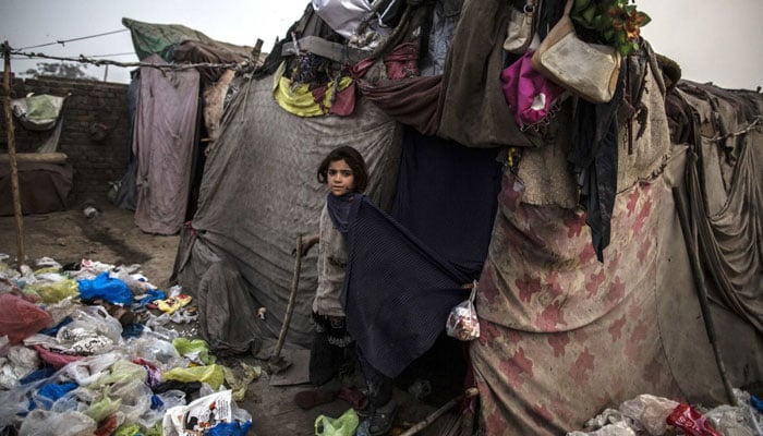 An Afghan refugee girl stands near her parents