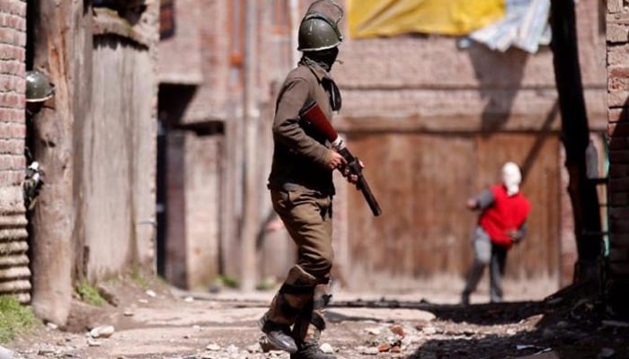 A Kashmiri demonstrator (R) throws a stone towards an Indian policeman during a protest against by-polls in Srinagar - Reuters