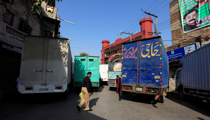 A policeman walks next to trucks, which used to block a venue of a planned protest gathering organised by Awami Muslim League