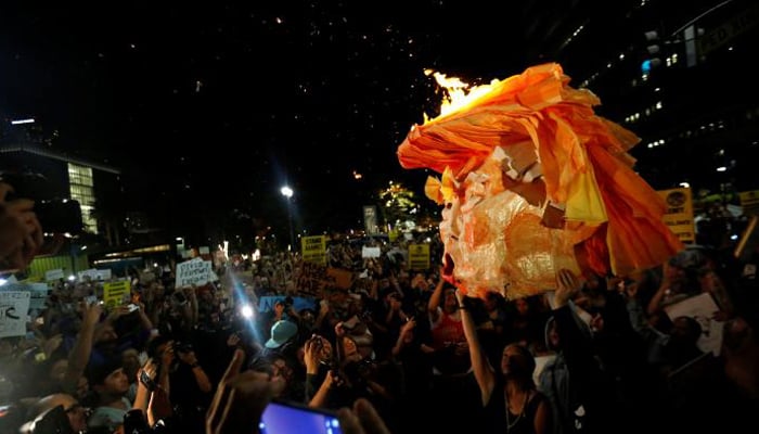 People hold a pinata which was lit on fire while protesting the election of Republican Donald Trump as the president of the United States in downtown Los Angeles, California US- REUTERS