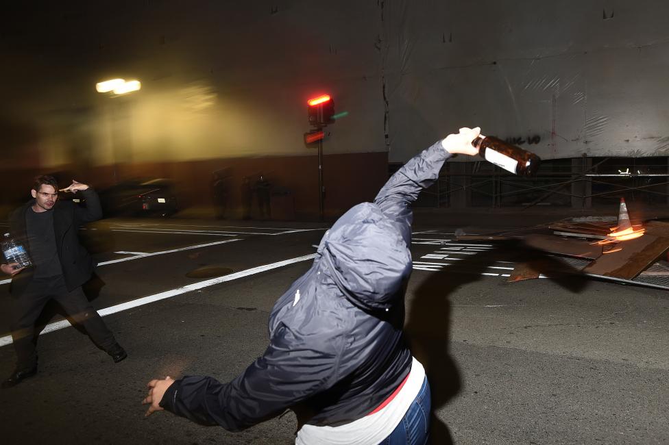 A protester throws a bottle at police officers following the election of Donald Trump in Oakland.