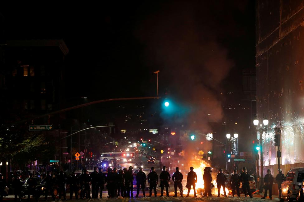 Police officers form a line after demonstrators set a street on fire on Telegraph Avenue in Oakland. 
