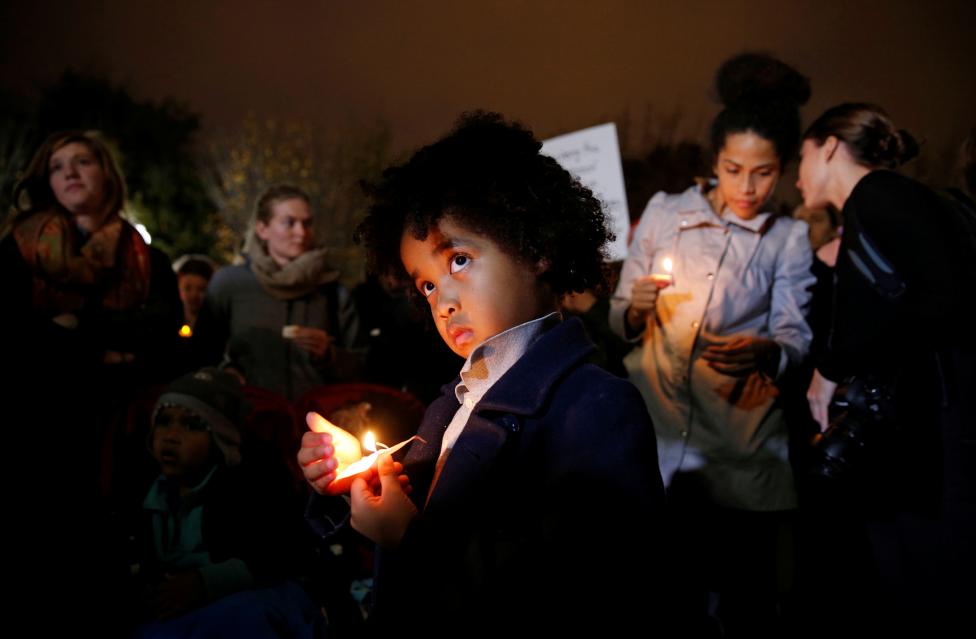A young boy stands with other anti-Trump demonstrators during a candlelight vigil in front of the White House. 