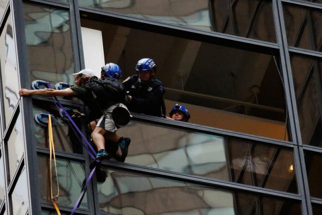 Officers from the NYPD embrace a man to stop him from climbing the outside of Trump Tower in New York, U.S., August 10, 2016.