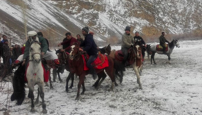Pakistani horsemen compete for a cattle carcass during a game of the traditional sport of Buzkashi in snow covered Chapursan village of Hunza Valley/AFP