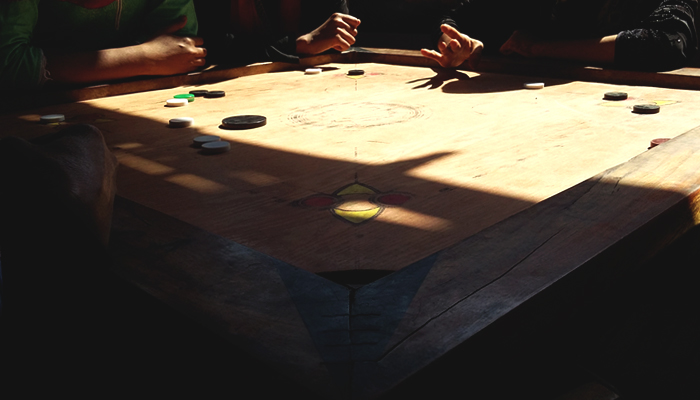 Girls hit and strike on a carrom board