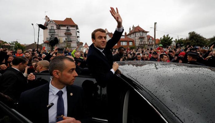 Macron greets supporters as he leaves a polling station/Reuters 