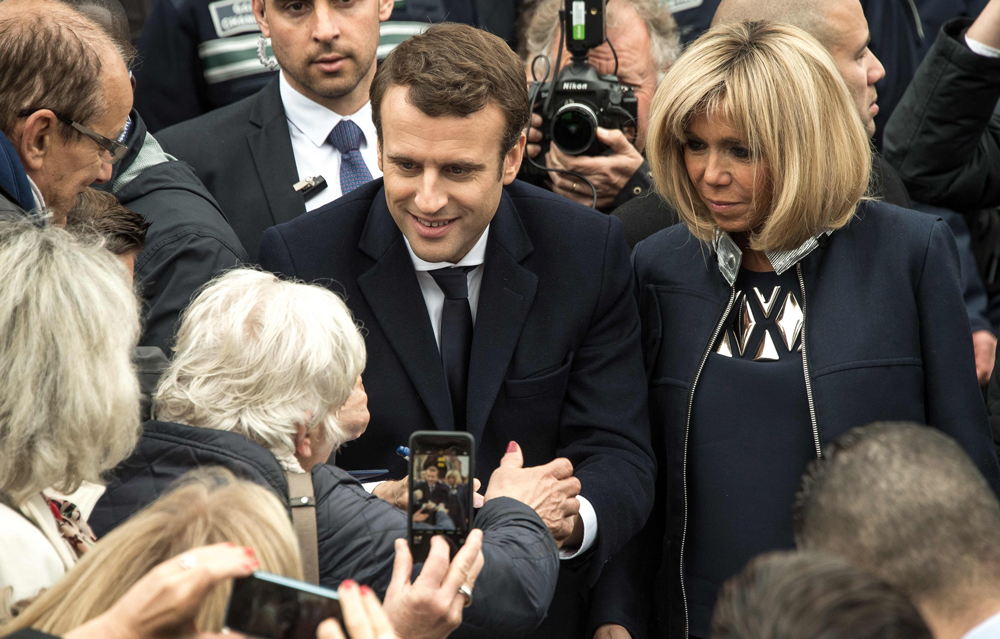 French presidential election candidate for the En   Marche ! movement Emmanuel Macron (C), next to   his wife Brigitte Trogneux (R), speaks with   supporters in Le Touquet, northern France, on May   7, 2017, after voting for the second round of the   French presidential election. / AFP / PHILIPPE   HUGUEN