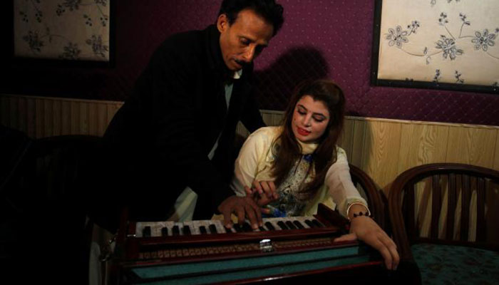 null Malala Gul, a local singer learns harmonium tips from her father as she prepares to record a song at a studio in Peshawar- REUTERS