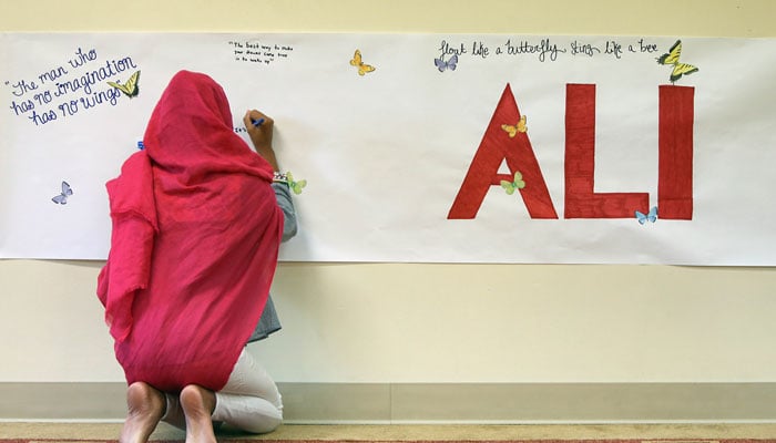 A worshipper writes a mesage on a banner during an interfaith memorial service for former heavy weight boxing champion Muhammad Ali at the River Road Mosque on June 5, 2016 in Louisville, Kentucky- AFP