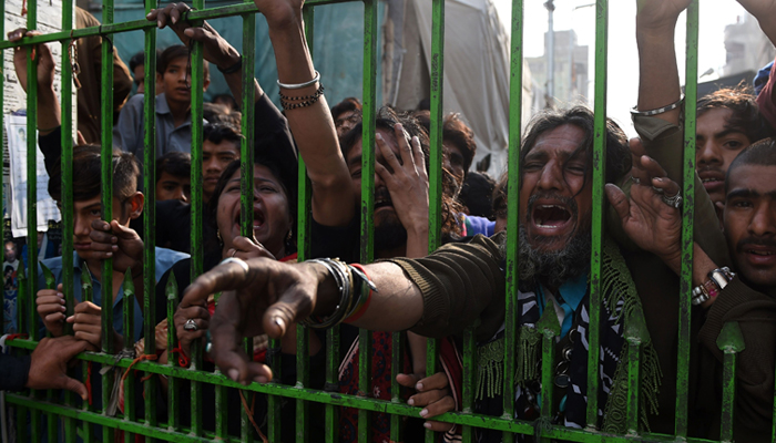 Pakistani devotees react as they gather outside the closed gate of the shrine of 13th century Muslim Sufi saint Lal Shahbaz Qalandar a day after AFP / ASIF HASSAN