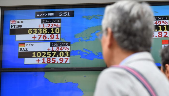 Pedestians walk past an electronic stock indicator of the London stock exchange (FT100) in the window of a securities company in Tokyo on June 24, 2016- AFP