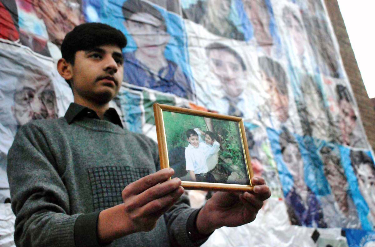 A boy holds picture of his brother martyred in APS terrorist attack/APP