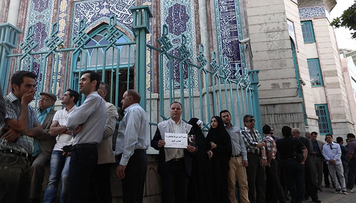 Iranians wait in a queue for the opening of the polling station to cast their ballots for the presidential elections in Tehran- AFP
