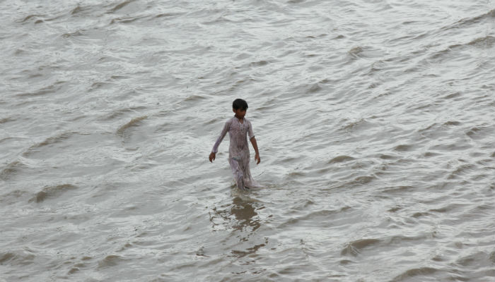 A boy wades through flooded street after the rain in Karachi. PHOTO: REUTERS