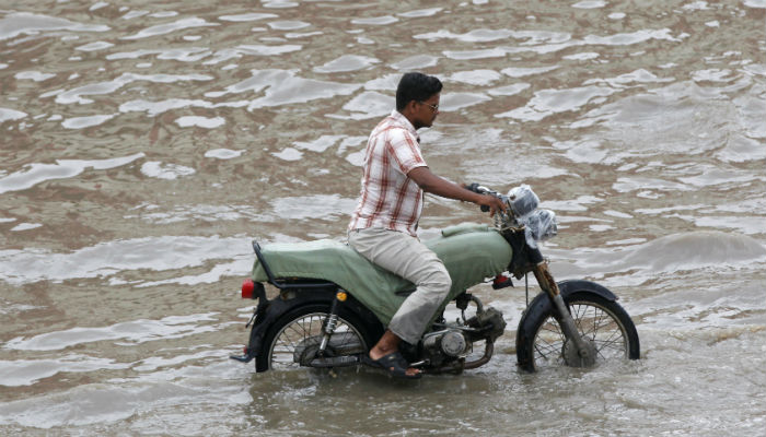 A man rides on a bike along a flooded street after the rain in Karachi. Photo: REUTERS