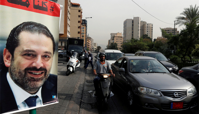 Cars pass next to a poster depicting Former Prime Minister Saad al Hariri in Beirut Lebanon