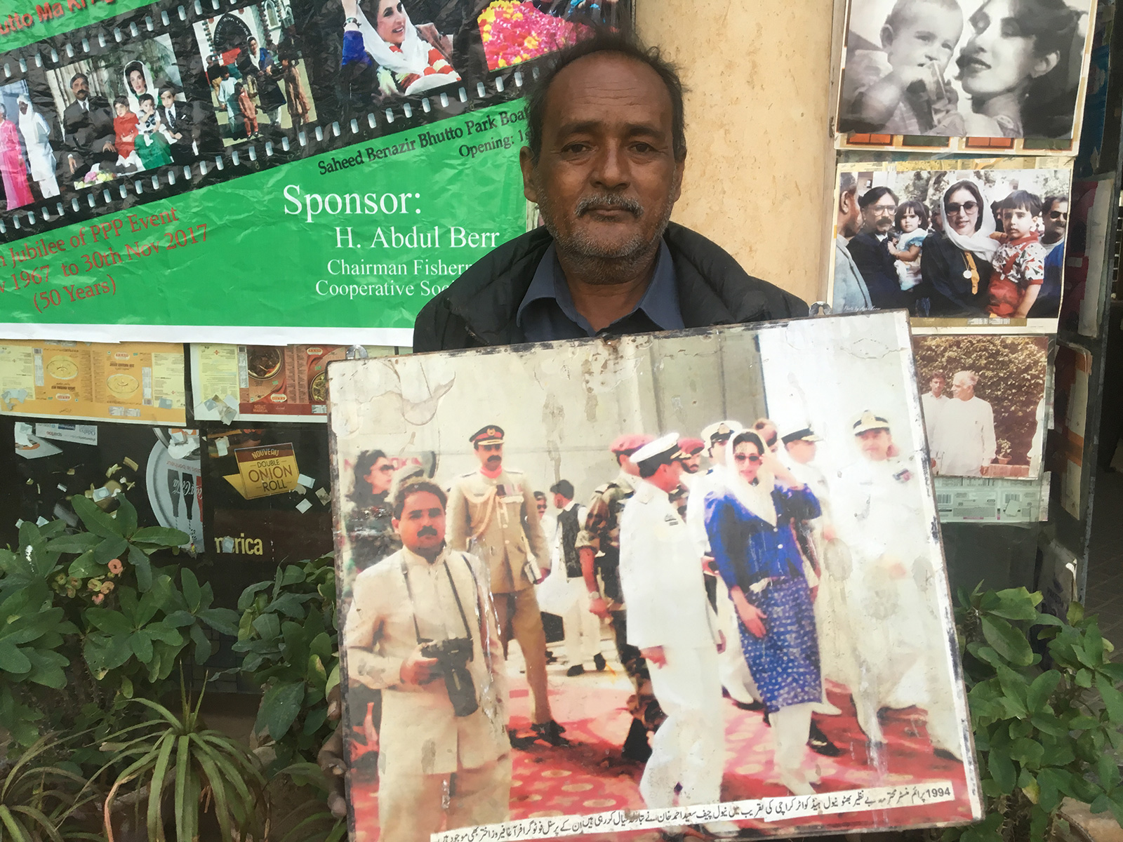 Benazir Bhutto's personal photographer Agha Feroze pictured here with a photo of himself with the former prime minister.—Photo by Ali Tariq/Geo.TV