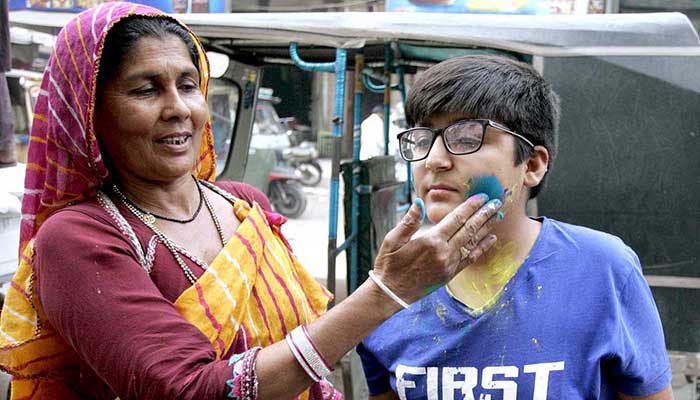 A Hindu lady colouring a child’s face to celebrate their religious festival Holi the Spring Festival of Colours at Tower Market - APP