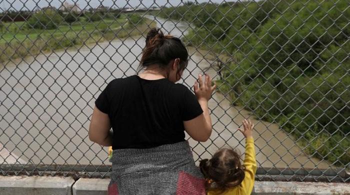 US government says it will detain migrant children with parents  A Honduran mother and her 3-year-old daughter seeking asylum wait on the Mexican side of the Brownsville-Matamoros International Bridge after being denied entry by US Customs and Border Protection officers near Brownsville, Texas, US, June 24,...