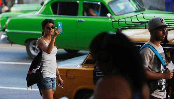 A woman uses the internet on her mobile phone at a hotspot in Havana Cuba