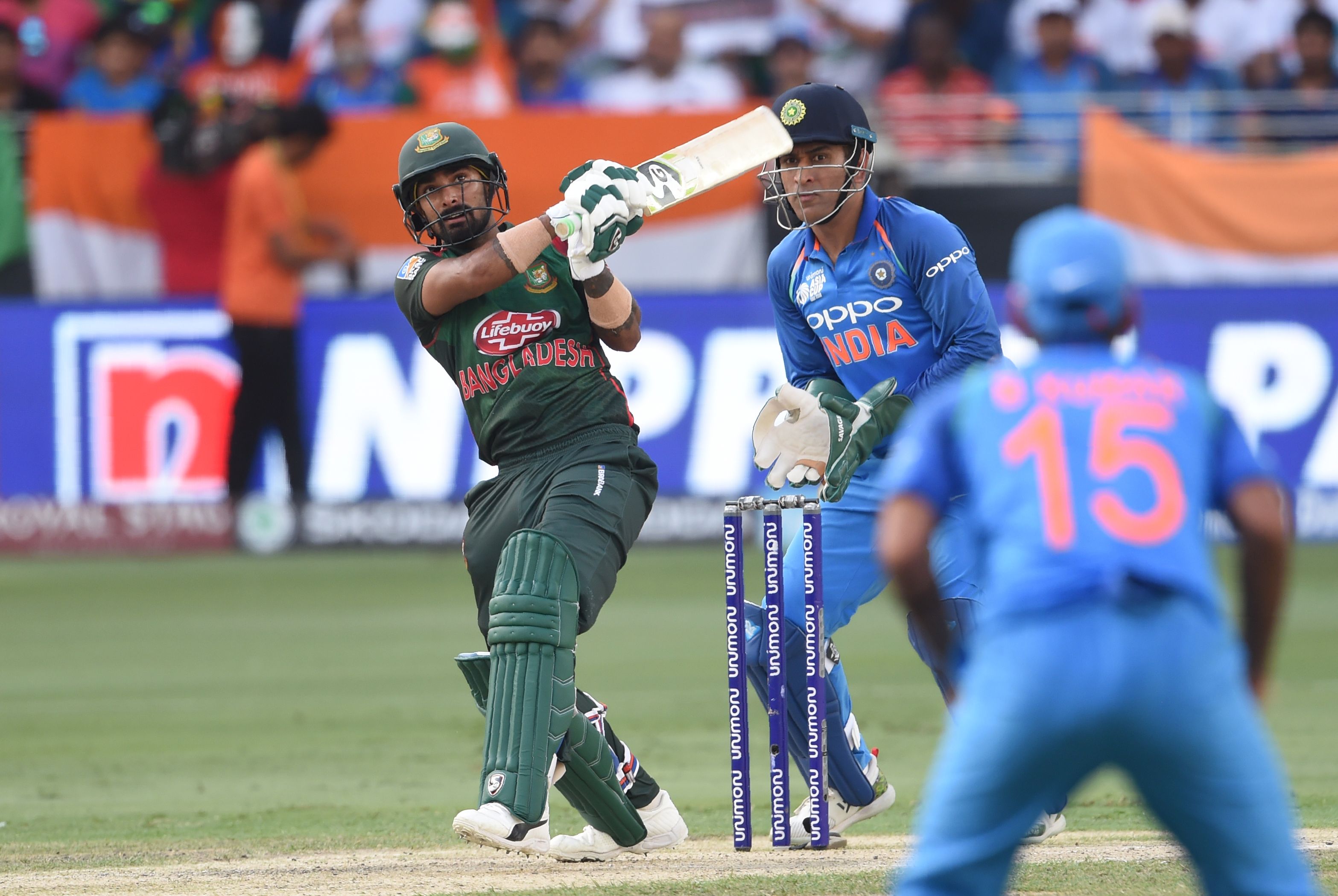 Bangladesh batsman Liton Das plays a shot as Indian wicketkeeper Mahendra Singh Dhoni (L) looks on during the final one day international (ODI) Asia Cup cricket match between Bangladesh and India at the Dubai International Cricket Stadium in Dubai on September 28, 2018. / AFP 