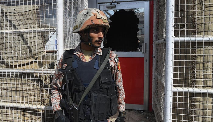 A Pakistani ranger stands in front of a damaged gate at the Chinese consulate after an attack in Karachi on November 23, 2018 - AFP