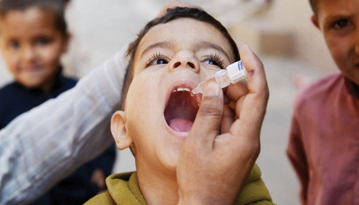 Undaunted female health worker administers anti-polio drops on a bike