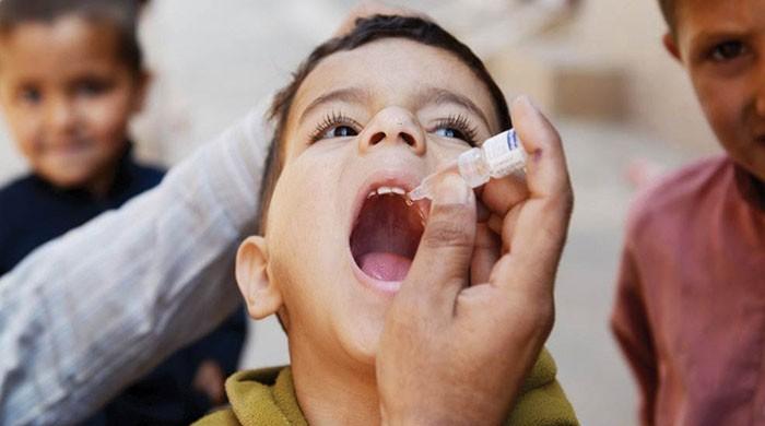 Undaunted female health worker administers anti-polio drops on a bike