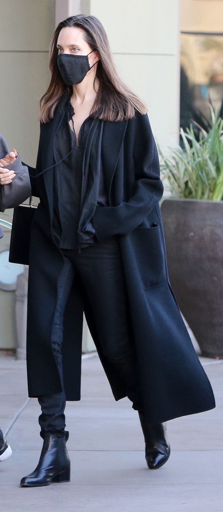 Angelina Jolie in a Chic Long Black Overcoat and Carrying a Dior