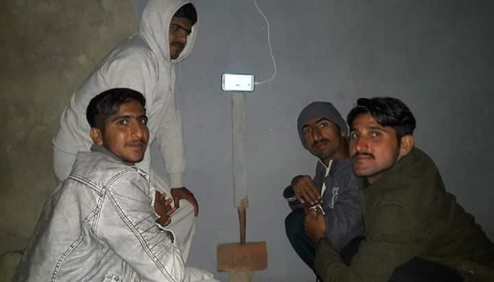 Shahnawaz Dahani and his friends trying to watch the live stream of a cricket match on a makeshift TV in their village.