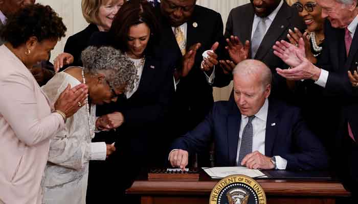 US President Joe Biden is applauded as he reaches for a pen to sign the Juneteenth National Independence Day Act into law as Opal Lee, a 94-year-old activist and retired educator in Fort Worth, Texas, reacts with Vice President Kamala Harris in the East Room of the White House in Washington, US, June 17, 2021. — Reuters/Carlos Barria