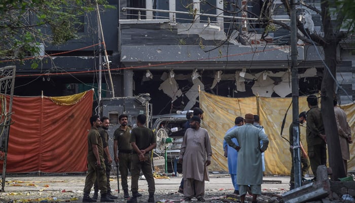 Police and locals stand near the site of an explosion in Lahore on June 24, 2021, a day after a car bomb killed three people in Pakistan´s eastern megacity. — AFP/File