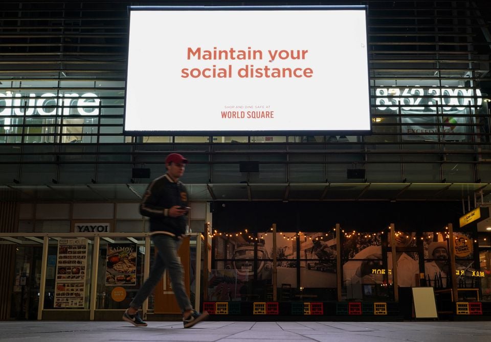 A man walks under a public health message about social distancing displayed at a shopping plaza in the city centre during a lockdown to curb the spread of a coronavirus disease (COVID-19) outbreak in Sydney, Australia, July 6, 2021. Photo: Reuters