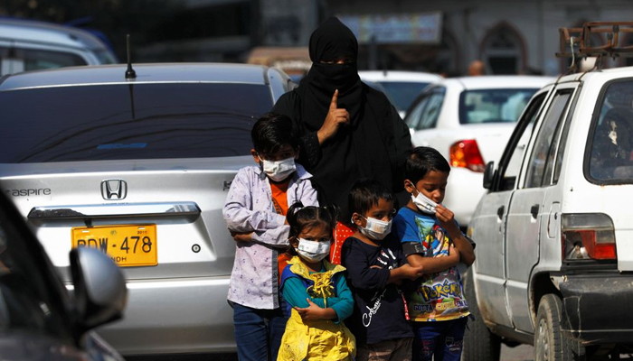 Children wear protective masks as they wait with their mother to cross the road, as the outbreak of the coronavirus disease (COVID-19) continues in Karachi, Pakistan. Picture taken January 15, 2021. — Reuters/File