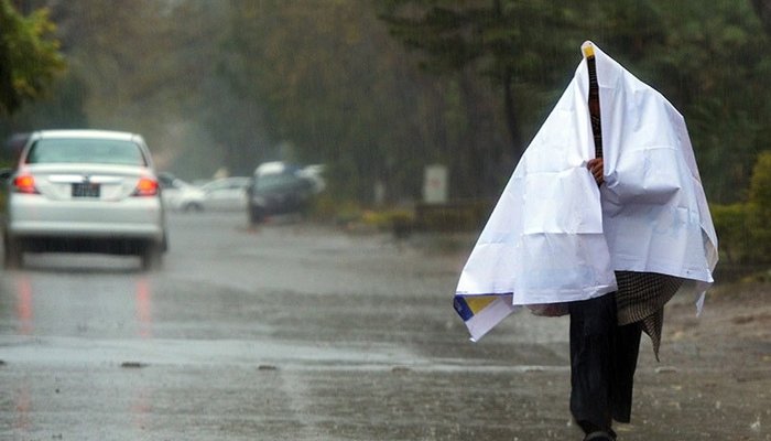 A man walking down the road and covering himself during rain. Photo: AFP
