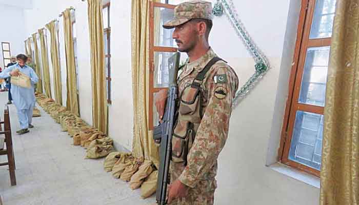 A soldier stands alert in Muzaffarabad as poll officials bring election material to a polling station in this 2016 file photo. — APP
