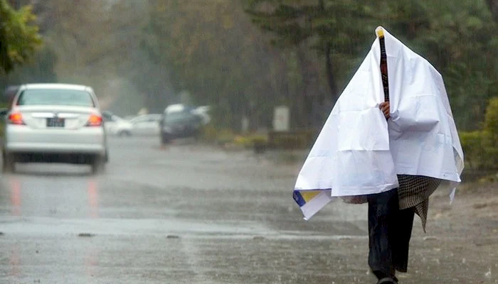 A man walking down the road and covering himself during rain. — AFP/File