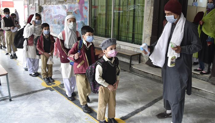 Student wear face masks as they arrive at their school at Peshawars Gulbhar colony, on February 1, 2021. — INP/File