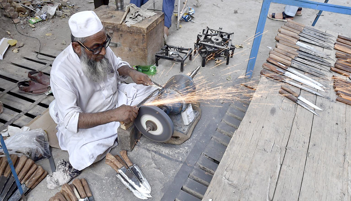 A blacksmith can be seen busy sharping knives to be used in slaughtering sacrificial animals in Peshawar, on July 11, 2021. — INP/File