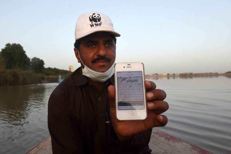 In this photograph taken on March 23, 2021, Abdul Jabbar, a member of the World Wildlife Fund (WWF) dolphin rescue team, shows an awareness message written in Urdu for the community to protect and conserve endangered Indus river dolphins, during a monitoring routine along the Indus river near the southern Sindh province city of Sukkur. — AFP