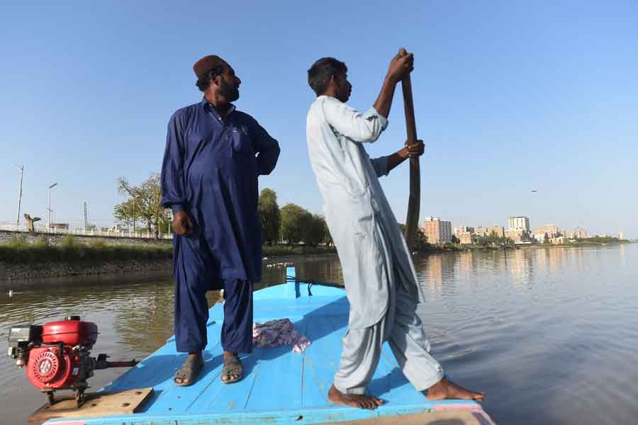 In this photo taken on March 23, 2021, Ghulam Akbar (left), a local fisherman and volunteer of the Indus Dolphin Rescue Team, stands during routine monitoring along the Indus River near Sukkur, southern Sindh. On board. — Agence France-Presse