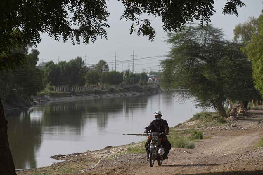 In this photograph taken on March 24, 2021, Abdul Jabbar, a member of World Wildlife Fund (WWF) dolphin rescue team, rides on a bike along a canal during a monitoring routine near the southern Sindh province city of Sukkur. — AFP